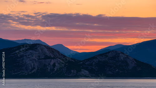 A photo of a sunset over the mountains. The sky is painted with shades of orange, pink, and purple. photo