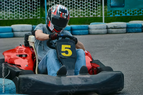 A racer in a helmet driving a rental go-kart on the track, participating in go-karting, go-kart racing. photo