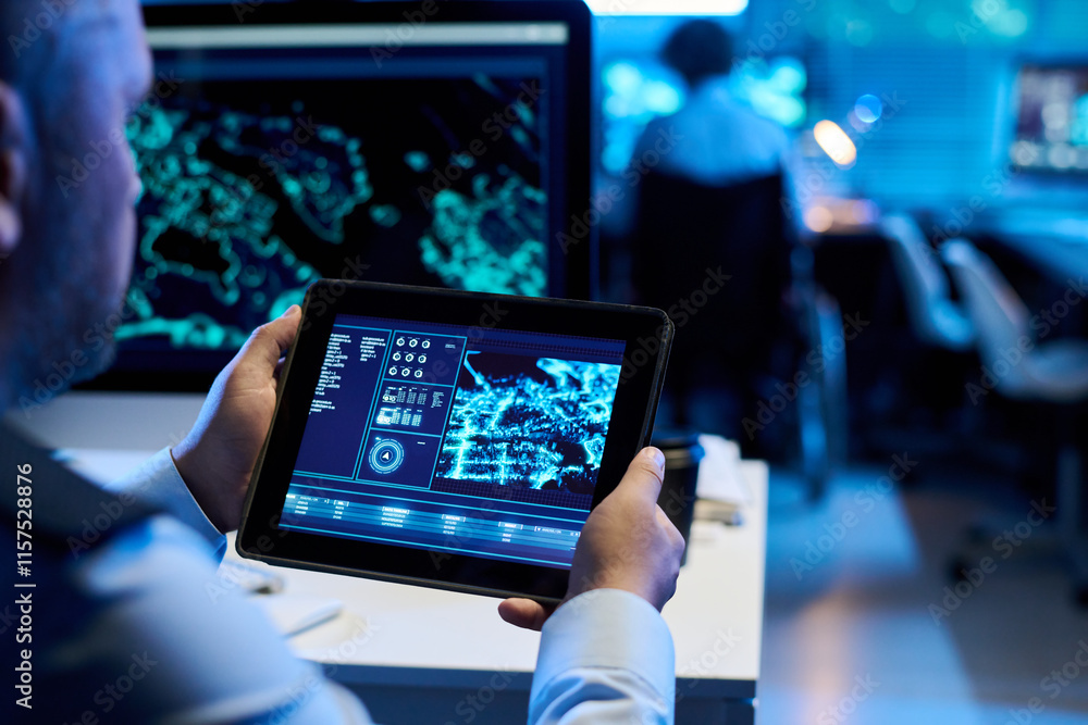 Digital tablet with graphic data on screen held by mature male operator in uniform sitting by workplace in military office Digital tablet with graphic data on screen held by mature male operator in uniform sitting by workplace in military office