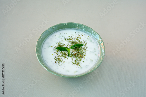 Tzatziki, cacik, or tarator is a traditional Turkish and Greek appetizer made from fresh yoghurt, cucumbers, spices and olive oil in a white plate. 