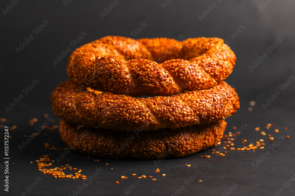 Savory sesame rings stacked on a dark surface with scattered seeds Savory sesame rings stacked on a dark surface with scattered seeds