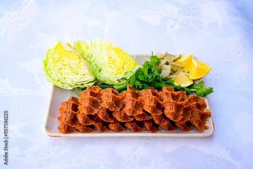 Cig kofte (raw meatball) with lettuce, tomato, pickle and lemon, hot Chee kofta. Turkish local raw food concept.Table scene of assorted take out or delivery foods. Doritoslu duble cig kofte durum. photo