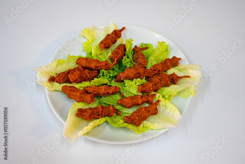 Cig kofte (raw meatball) with lettuce, tomato, pickle and lemon, hot Chee kofta. Turkish local raw food concept.Table scene of assorted take out or delivery foods. Doritoslu duble cig kofte durum. photo