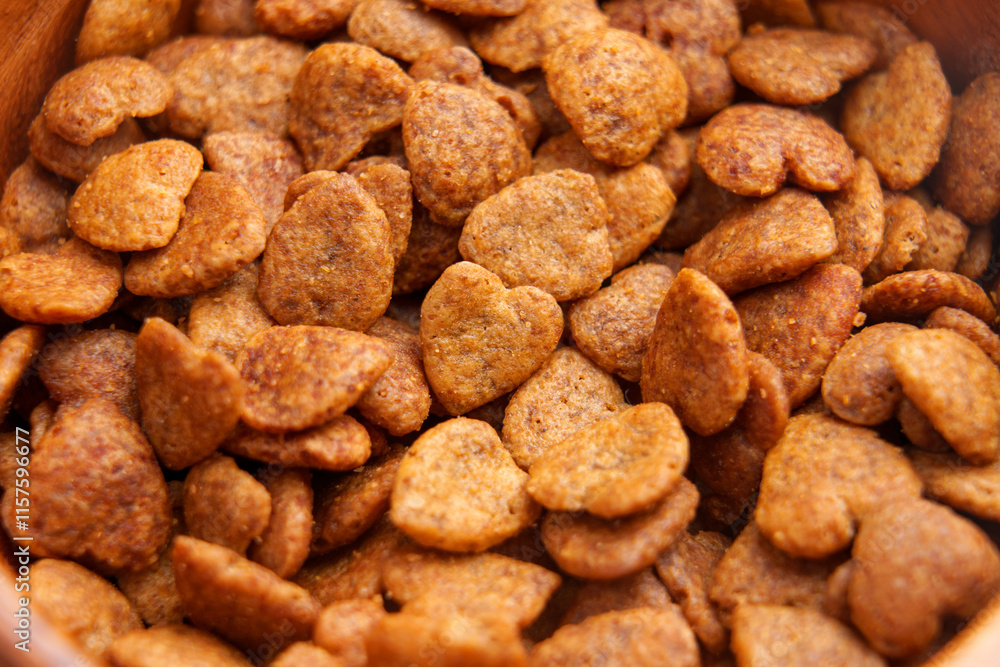 Cat crispy treats in heart shapes with brown crunchy texture in rustic wooden bowl. Pet food. Close up. Top view Cat crispy treats in heart shapes with brown crunchy texture in rustic wooden bowl. Pet food. Close up. Top view