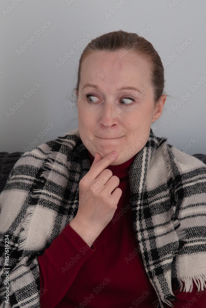 Mature beautiful thoughtful woman, in checkered scarf, sitting on sofa, thinking about important question. Concept of doubt, worry, choice, negative emotions, sadness, stress, unexpected news. Mature beautiful thoughtful woman, in checkered scarf, sitting on sofa, thinking about important question. Concept of doubt, worry, choice, negative emotions, sadness, stress, unexpected news.