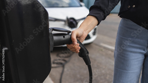 Canvas Print Woman holding power cable plugging into electric car charger in london