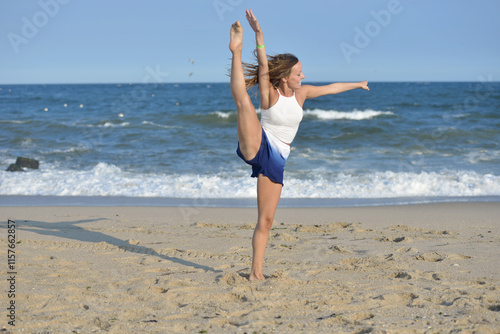 Beautiful young woman white tank top and blue & white skorts dances on the beach photo