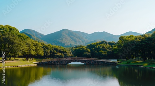 A stone bridge crossing a calm lake with a mountain view