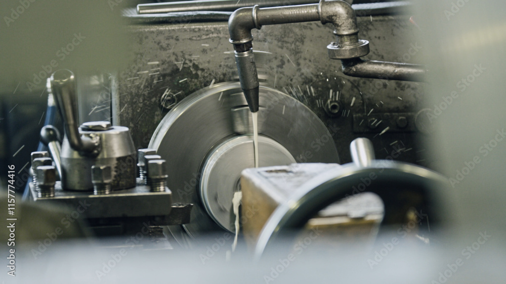 Obraz premium Close up view of cutting fluid being poured onto a metal piece during machining on an industrial lathe, generating swarf and ensuring optimal cooling and lubrication for precision work
