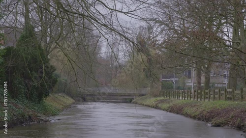 Quiet late-autumn view with leafless trees by a path/canal under soft grey light in Germany. 4K UHD.