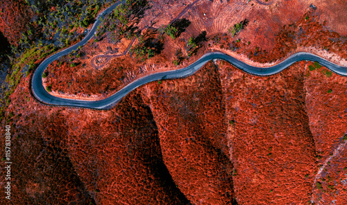 Rural curved and winding road perched above steep colored slopes.  Drone capture from above looking down. photo