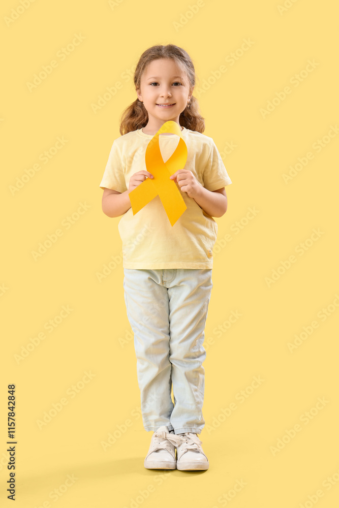 Cute little girl with yellow ribbon on color background. Childhood cancer awareness concept