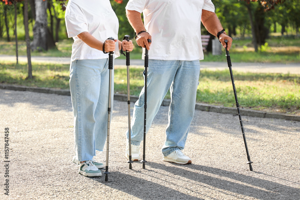Mature woman and man training with walking poles in park, closeup Mature woman and man training with walking poles in park, closeup