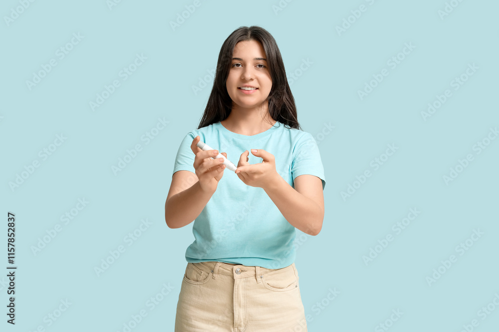 Diabetic young woman using lancet pen on blue background Diabetic young woman using lancet pen on blue background
