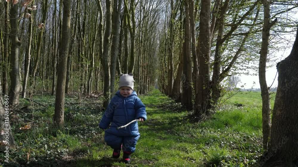 Joyful little child holds stick and happily roams through sunlit forest, surrounded by tall trees and vibrant greenery, fully immersed in enchanting beauty and magic of natures playful exploration Joyful little child holds stick and happily roams through sunlit forest, surrounded by tall trees and vibrant greenery, fully immersed in enchanting beauty and magic of natures playful exploration