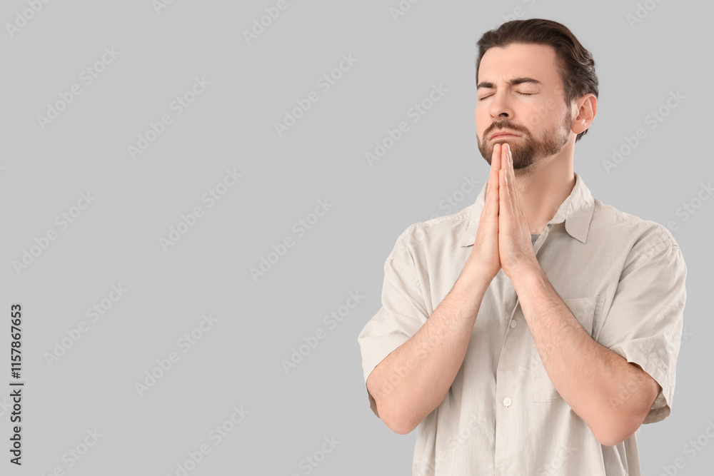 Religious man praying on grey background Religious man praying on grey background