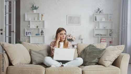 Obraz na plátně Young woman sitting on the sofa in her living room, struggling with her laptop a