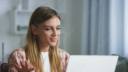 Young woman having a video conference on a laptop at home, gesturing with her hand and smiling, working remotely or connecting with friends and family Free Download Young woman having a video conference on a laptop at home, gesturing with her hand and smiling, working remotely or connecting with friends and family - GFXLoad