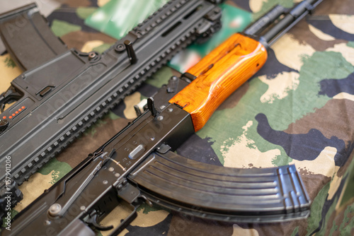 AK-47 Kalashnikov and a modern assault rifle on a camouflage tarp photo