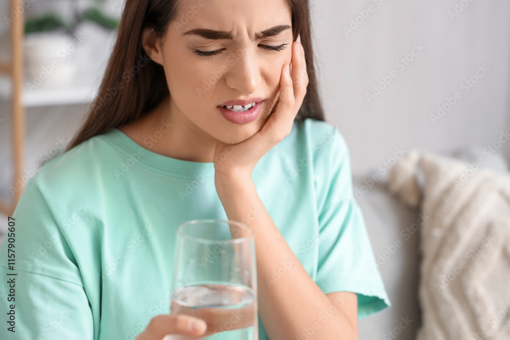 Young woman suffering from toothache with glass of water at home, closeup Young woman suffering from toothache with glass of water at home, closeup