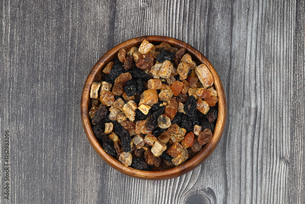 Mix of nuts and dried fruits in wooden bowl isolated on a wooden background. Mix of nuts and dried fruits in wooden bowl isolated on a wooden background.
