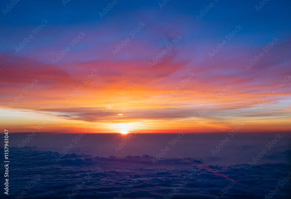 A vibrant sunset above soft, textured clouds in the foreground, blending shades of orange, pink, and blue in a serene sky A vibrant sunset above soft, textured clouds in the foreground, blending shades of orange, pink, and blue in a serene sky