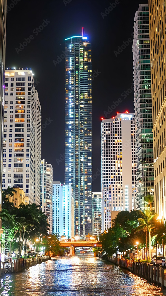 Fototapeta premium Night Cityscape, Illuminated Skyscrapers Reflecting on Calm Water, City Lights Glimmering on River, Urban Night Scene