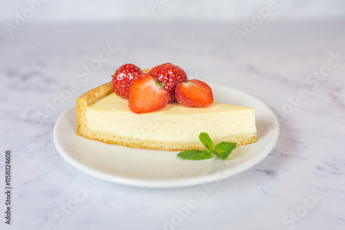 Fotografia Classic sliced homemade New York cheesecake with fresh strawberries served on a marble countertop