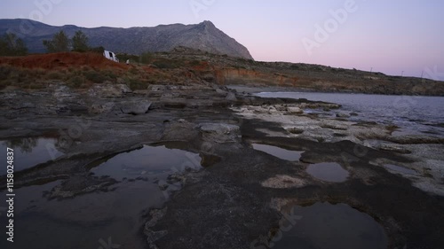 Natural holes on the rocks full with water at sunset with turquoise water sea of Greece on the background