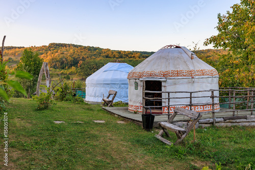 Two tents are in grassy field, one of which is white and the other is tan, kyrgyz authentic nomadic yurt photo