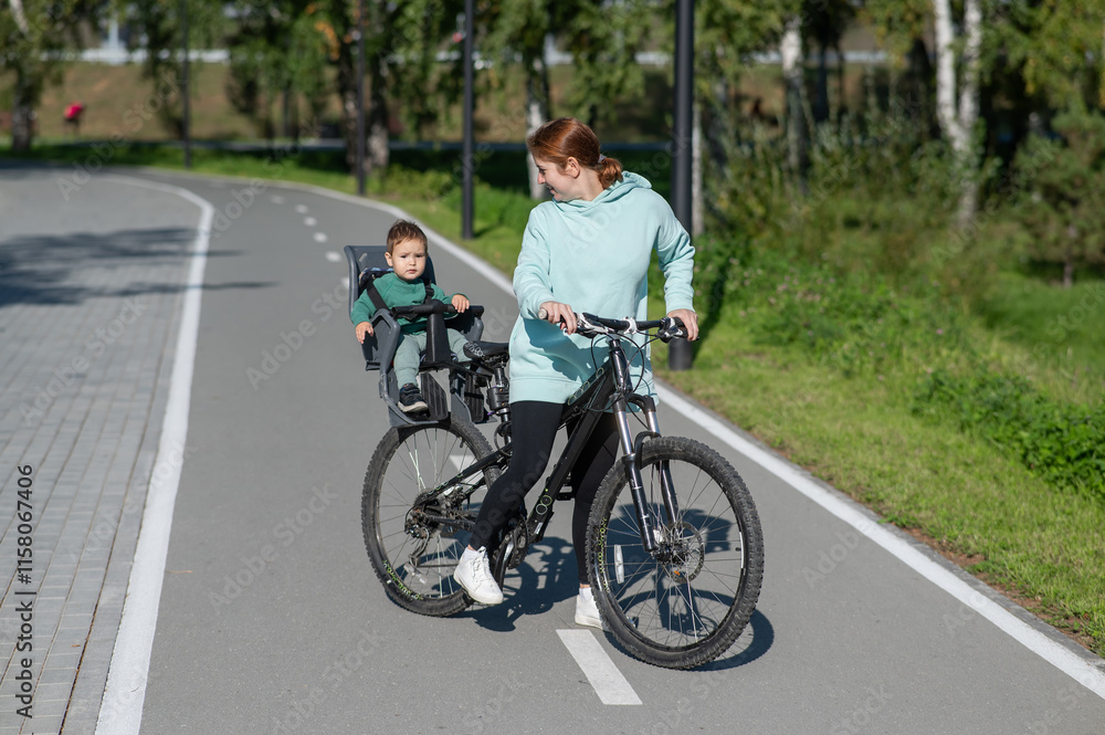 Caucasian woman riding a bicycle with her toddler son sitting behind her in a child seat. Caucasian woman riding a bicycle with her toddler son sitting behind her in a child seat.