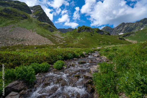 The valley of the Malaya Dukka River on the slopes of the Arkasar ridge in the North Caucasus and the tourist trail to the Dukka Lakes on a sunny summer day, Arkhyz, Karachay-Cherkessia, Russia photo