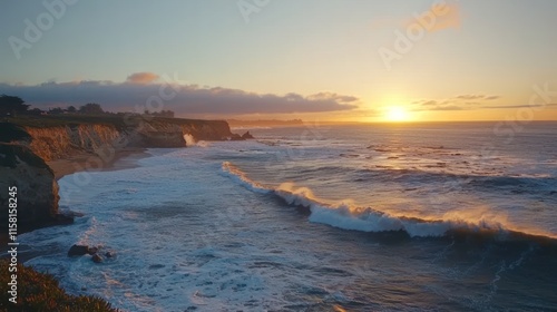 A serene coastal sunset over waves crashing on a sandy beach.