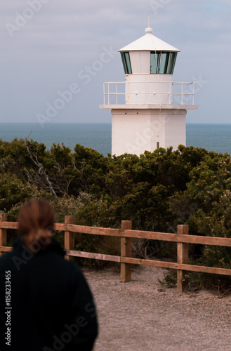 man walking to a lighthouse on the coast photo