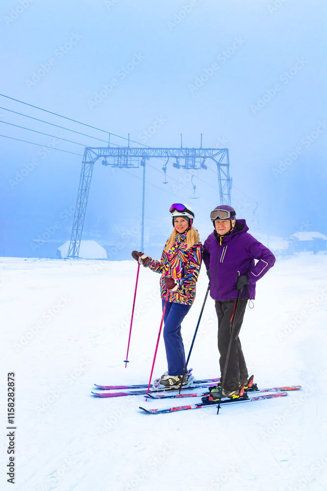 Two father and daughter skiers enjoying a beautiful day on the slopes surrounded by nature and snow