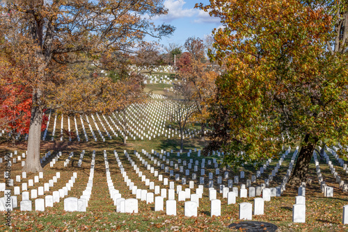 Serene autumn view of Arlington National Cemetery showcasing rows of white gravestones amidst colorful fall foliage. photo