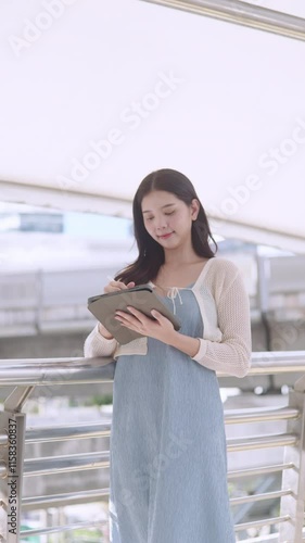 Asian woman is taking notes on a tablet.