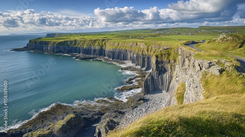 Dramatic coastal cliffs, ocean, road, green hills under a partly cloudy sky.