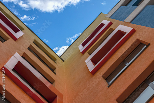 Upward view of colorful building corners with windows under a bright blue sky for architectural aesthetics