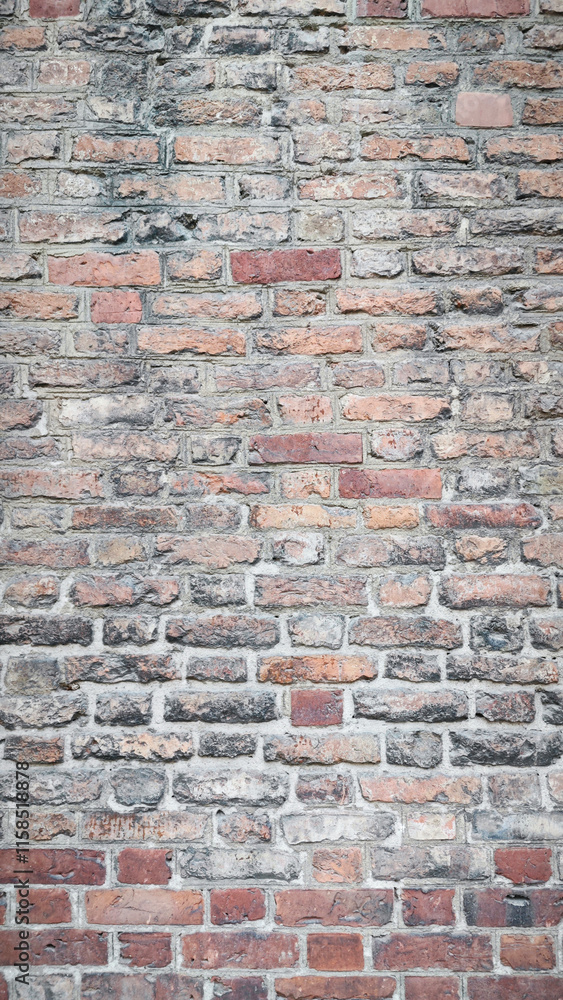 Fototapeta premium Weathered Vertical Brick Wall - Rustic Red and Gray Bricks with Aged Texture, Ideal for Architectural Backgrounds