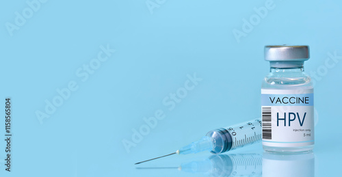 HPV Vaccine in a bottle with a syringe on a blue background. Experimental HPV vaccine vial for immunization against HPV disease. Copy space photo