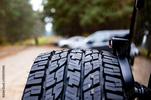 Obraz na płótnie Deep tread of a new off road tire mounted on the rear door of an off-road vehicle. The photo was taken during the day. w salonie