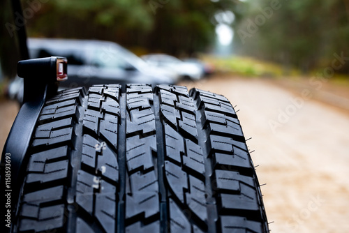Obraz na płótnie Deep tread of a new off road tire mounted on the rear door of an off-road vehicle. The photo was taken during the day. w salonie
