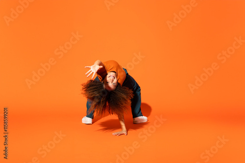 Young woman dancing in front of orange background photo