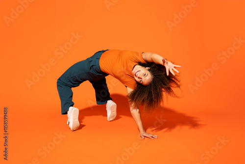 Happy woman bending over back in front of orange background photo