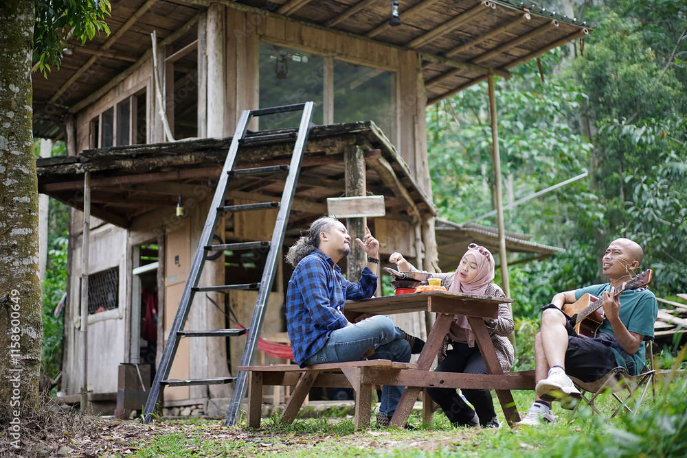 Indonesian man and woman in hijab relaxing in front of forest cabin, travel concept.