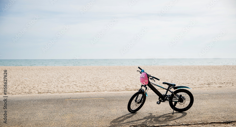 Obraz premium Enjoy the freedom of cycling by the sea, A child's bicycle on a sandy beach under a clear sky creating serene and beautiful seascape perfect for summer tourism adventure. bike in summertime vacations