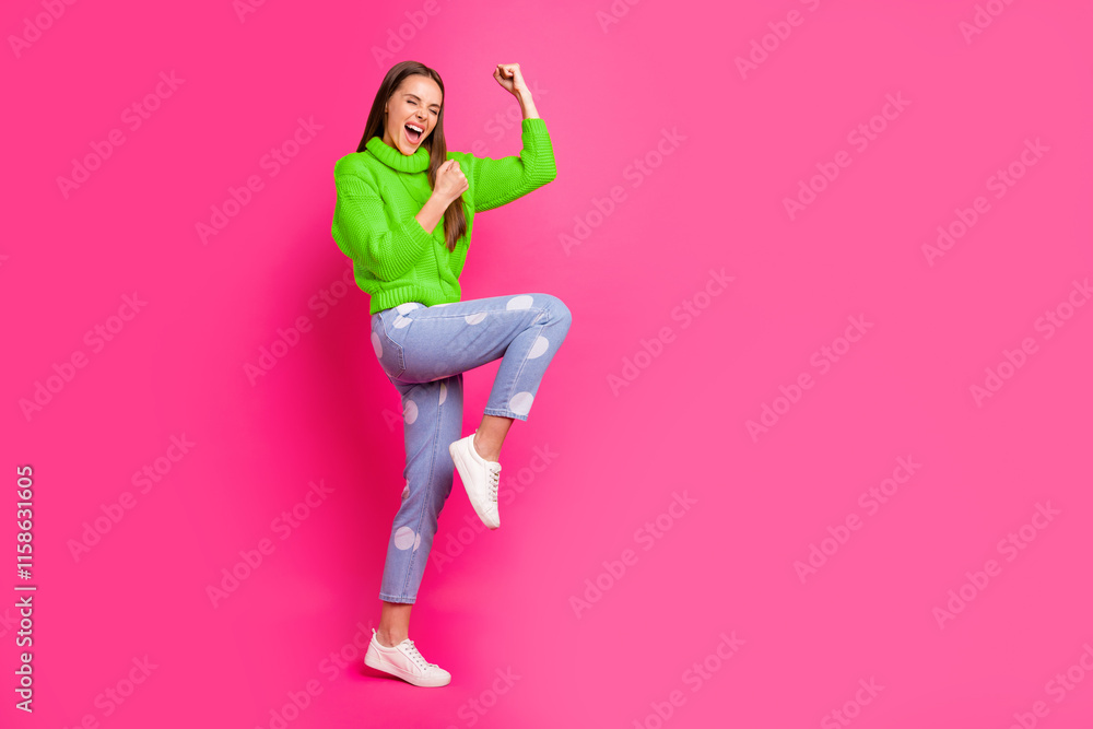 Full length photo of ecstatic girl raising her fists screaming yeah wearing yellow sweater dotted denim jeans isolated over fuchsia background Full length photo of ecstatic girl raising her fists screaming yeah wearing yellow sweater dotted denim jeans isolated over fuchsia background