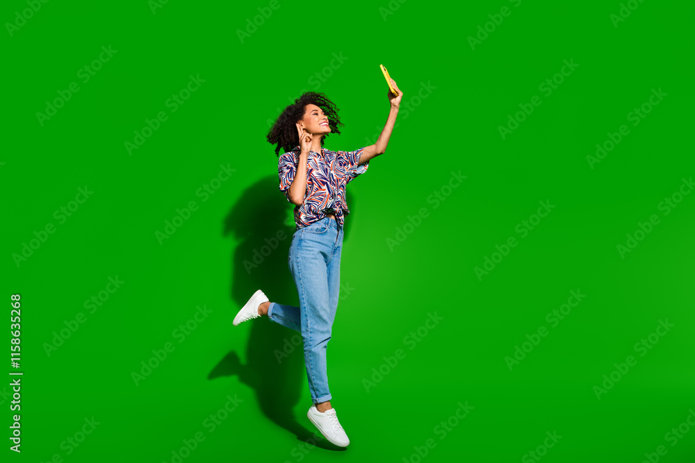 Full body photo of attractive young woman jump selfie photo v-sign dressed stylish colorful clothes isolated on green color background Full body photo of attractive young woman jump selfie photo v-sign dressed stylish colorful clothes isolated on green color background