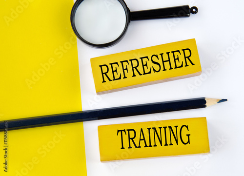 REFRESHER TRAINING - words on wooden yellow blocks with pencil and magnifying glass photo